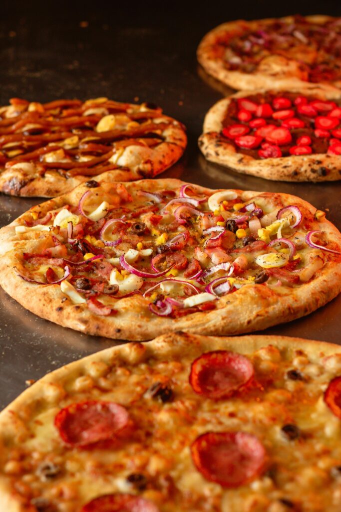 Close-up view of a variety of gourmet pizzas with diverse toppings on display.