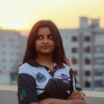 Portrait of a young woman in Dhaka, Bangladesh wearing a robotics-themed shirt at sunset.